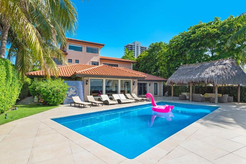 a swimming pool with a pink chair and a house at Villa Toscana - Luxury with Pool in Miami
