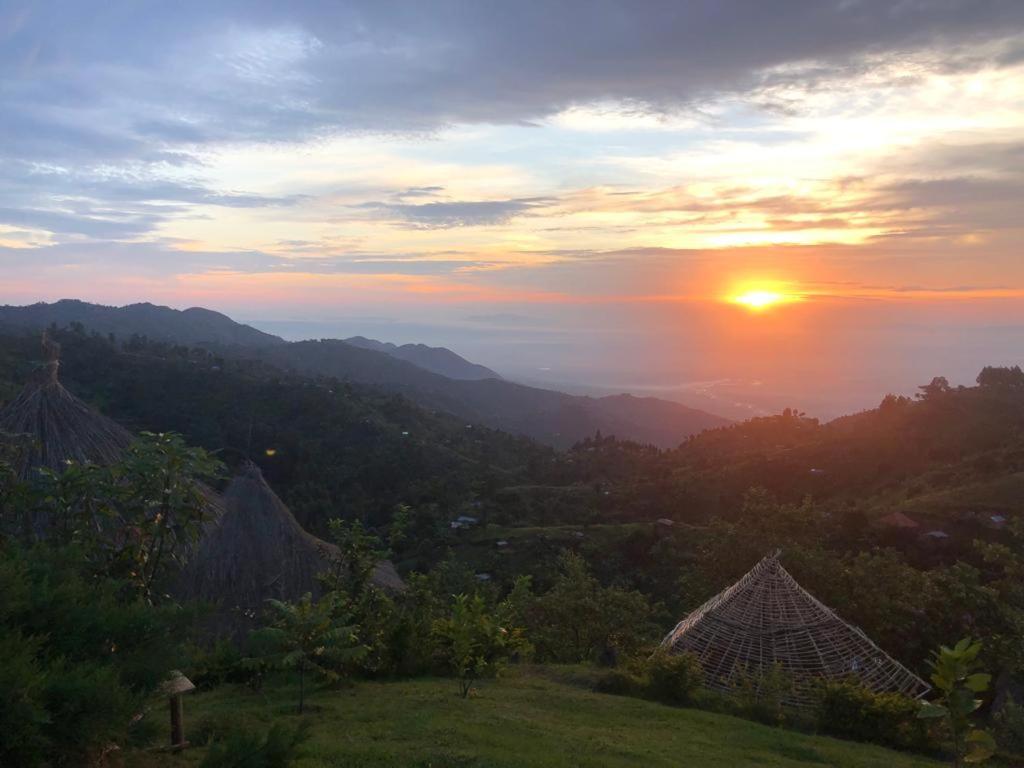 a sunset over a valley with the sun setting over mountains at Mbunga Community Tourism Campsite in Kasese