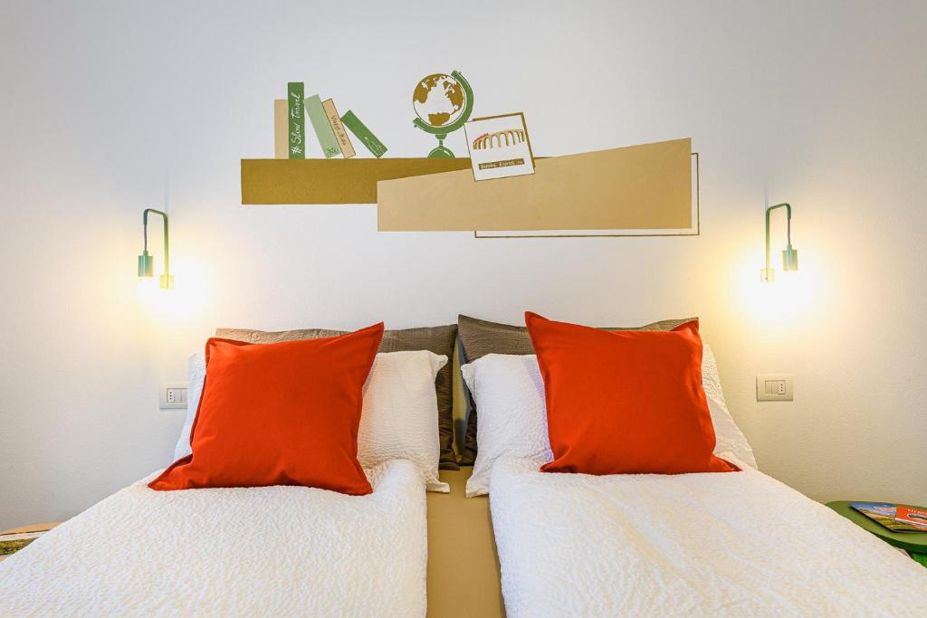 2 Betten mit orangefarbenen Kissen in einem Zimmer in der Unterkunft Alessia' s Home in Tirano