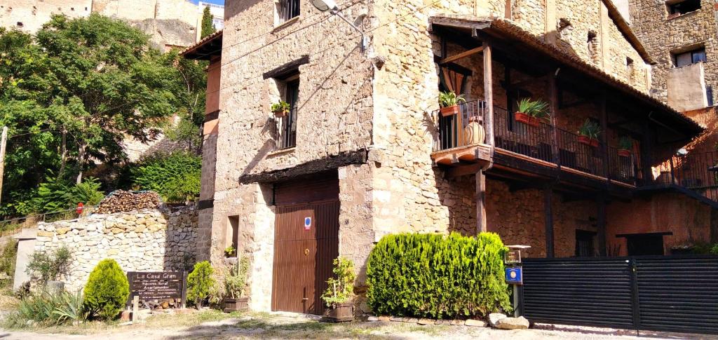 - un bâtiment en briques avec une porte en bois et un balcon dans l'établissement La Casa Gran, à Castielfabib