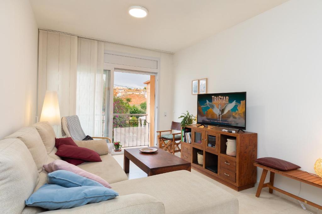a living room with a couch and a tv at Hauzify I Apartament Capmany in Sant Feliu de Guíxols
