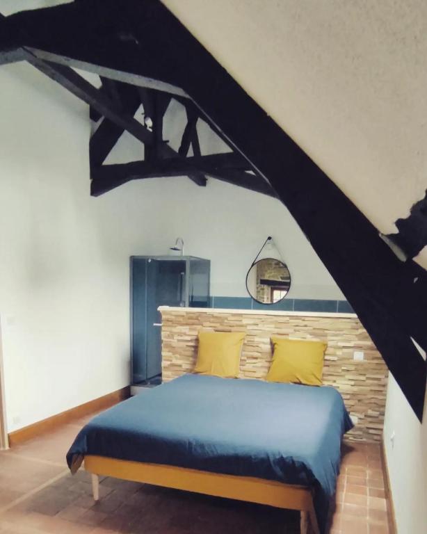 - une chambre avec un lit bleu et des oreillers jaunes dans l'établissement La grange de l'épine, à Forges-la-Forêt