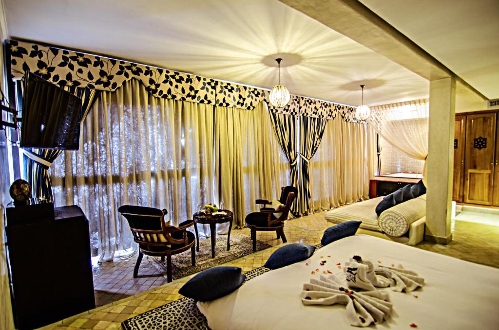 Palais Ommeyad Suites & Spa في فاس: غرفة فندقية بسريرين وكراسي وستائر