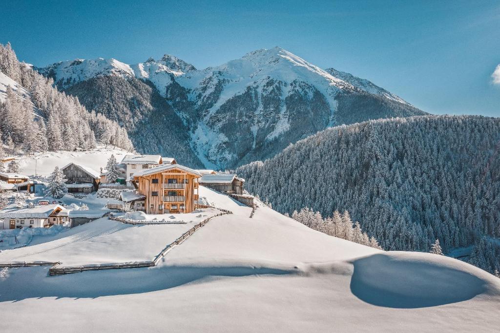 un complexe dans la neige avec des montagnes en arrière-plan dans l'établissement Bio & Reiterhof der Veitenhof, à Umhausen