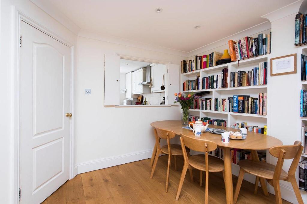 ein Esszimmer mit einem Tisch und Bücherregalen in der Unterkunft Lovely 2 Bedroom Family Home near Tower Bridge in London