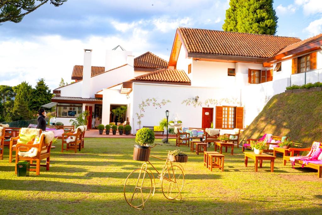 uma casa com um quintal com cadeiras e mesas em Pousada Hortelã em Campos de Jordão