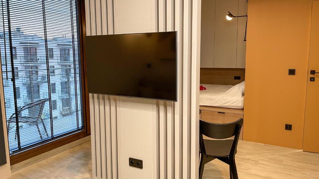 een kamer met een tv aan de muur met een stoel bij Comfortable 1-room apartment close to the center in Warschau