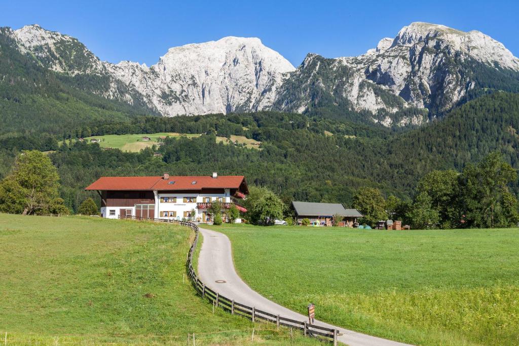 una casa en un campo con montañas al fondo en Gästehaus Untersulzberglehen, en Schönau am Königssee