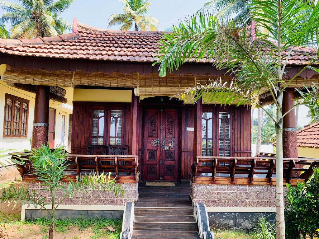 a house with a red door and some palm trees at Kerala cottage in Varkala