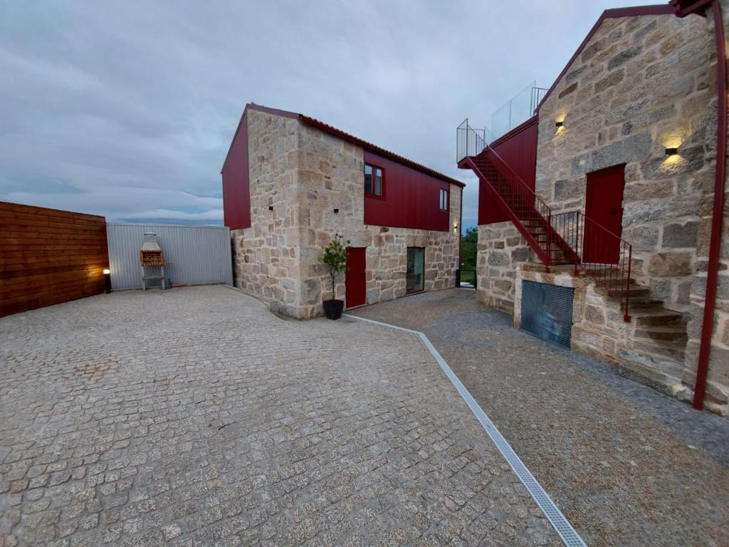 un edificio de ladrillo con puertas rojas y una escalera. en Casa de Penedones - Ventos do Larouco, en Penedones