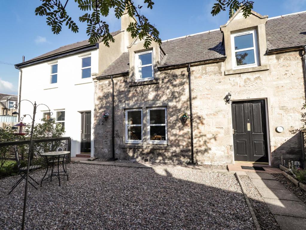 an old stone house with a table in front of it at 62 Society Street in Nairn