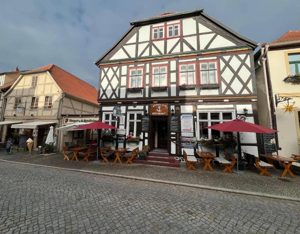 ein Gebäude mit Tischen und Sonnenschirmen auf einer Straße in der Unterkunft Hotel am Rathaus Adii in Tangermünde