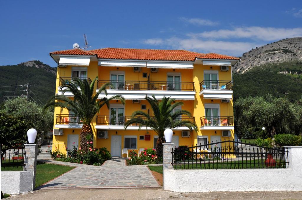 a yellow building with trees and mountains in the background at House Elena in Koinyra