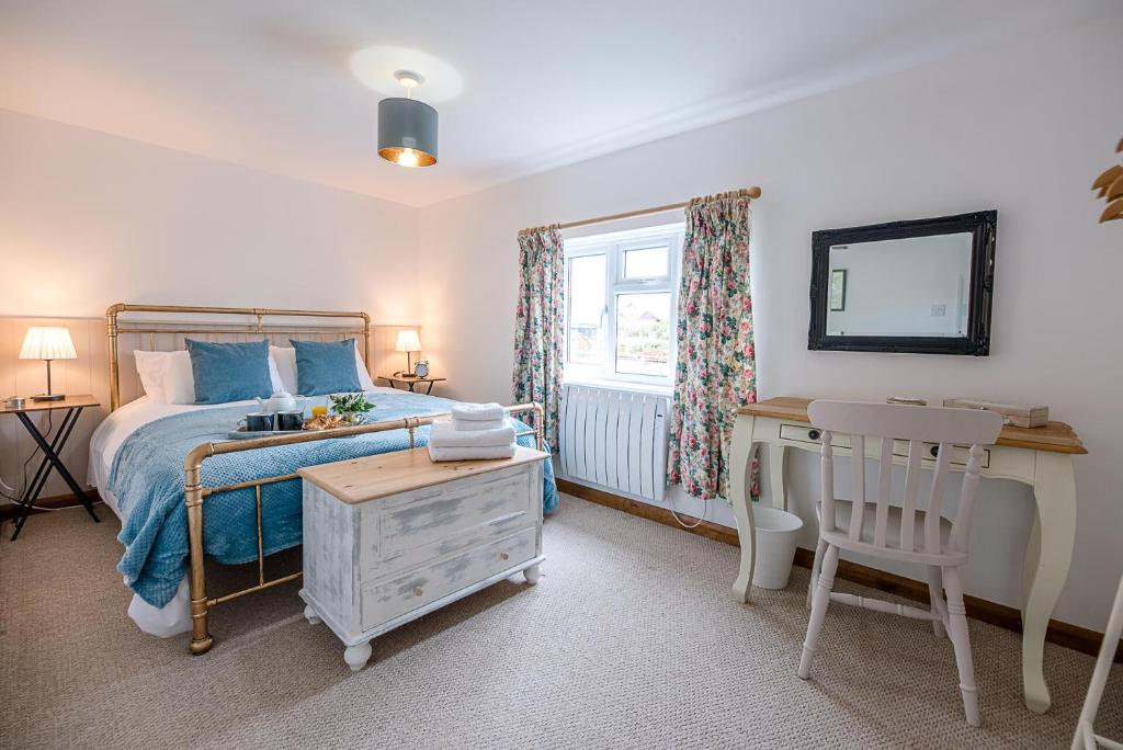 a bedroom with a bed and a desk and a window at North Cottage, Alderton in Woodbridge