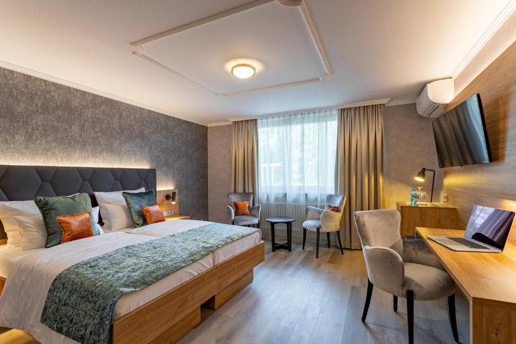Cette chambre comprend un lit et un bureau avec un ordinateur portable. dans l'établissement Villa Westend Hotel an der Messe, à Francfort-sur-le-Main