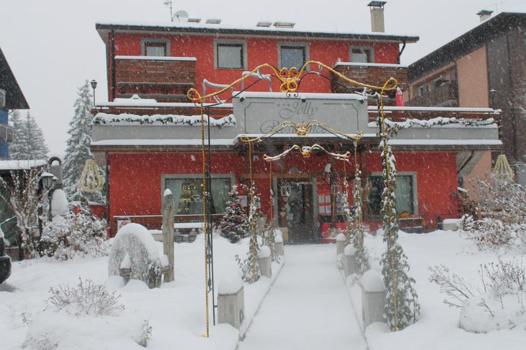 a red building with snow in front of it at Jolly Residence in Bormio