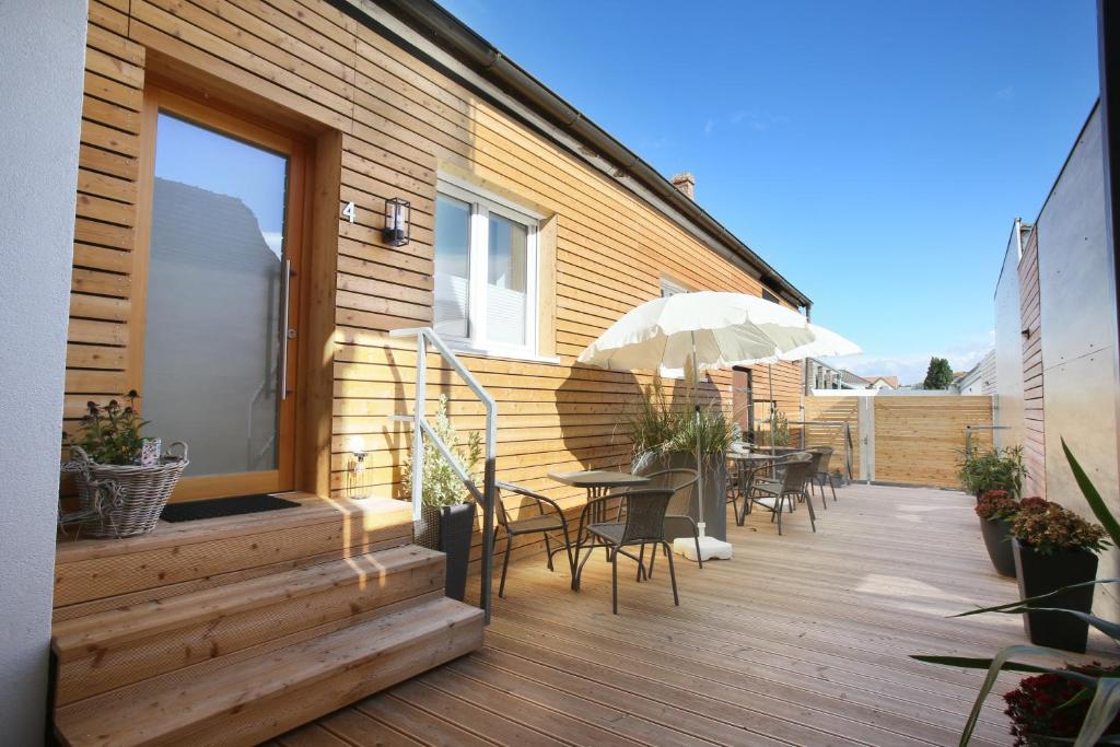 eine Terrasse mit einem Tisch, Stühlen und einem Sonnenschirm in der Unterkunft Apartments Freitag - H1 in Winden am See