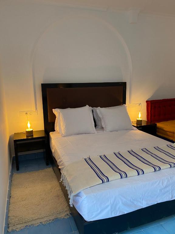 a bedroom with a bed with two tables and two lamps at Dmina House in Asilah
