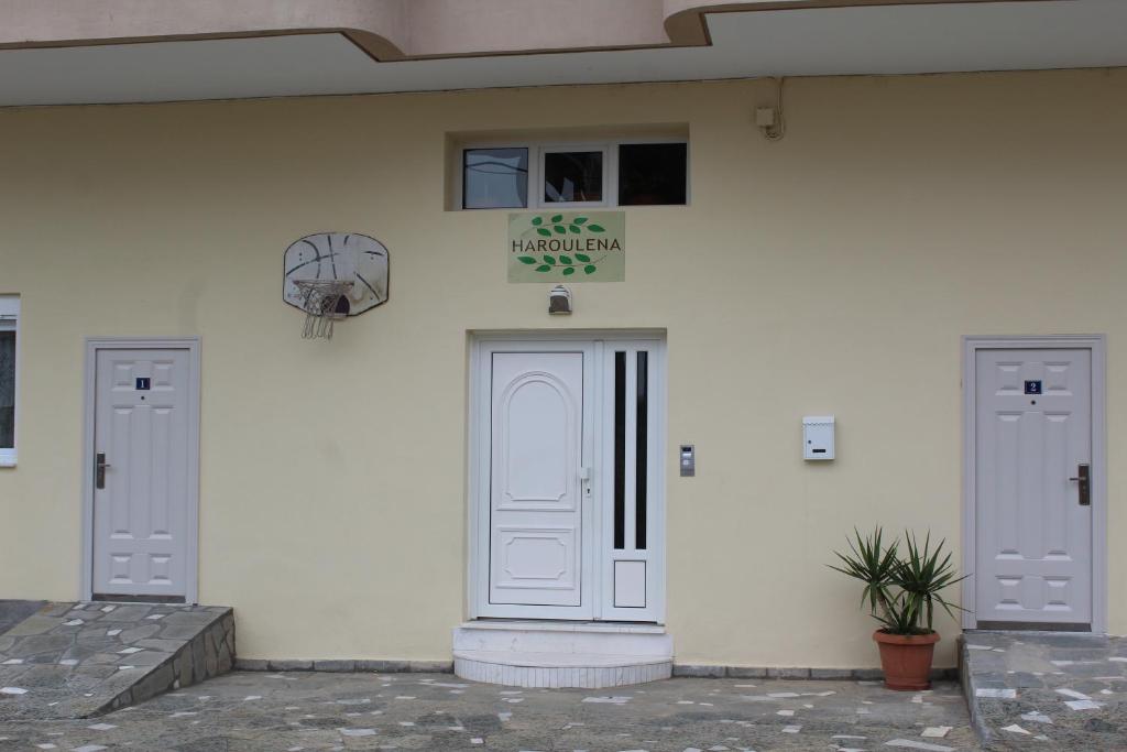 a white building with two doors and a plant at HAROULENA in Kavála