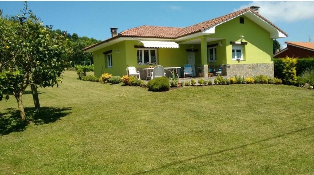 una casa verde con césped delante en Casina verde manzana, en Villaviciosa