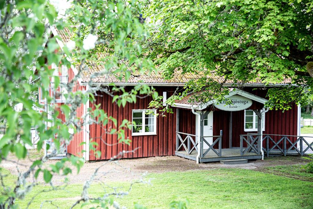 un edificio rojo con porche y ventana en Hofsnäs Lilla Sjöstuga en Hovsnäs