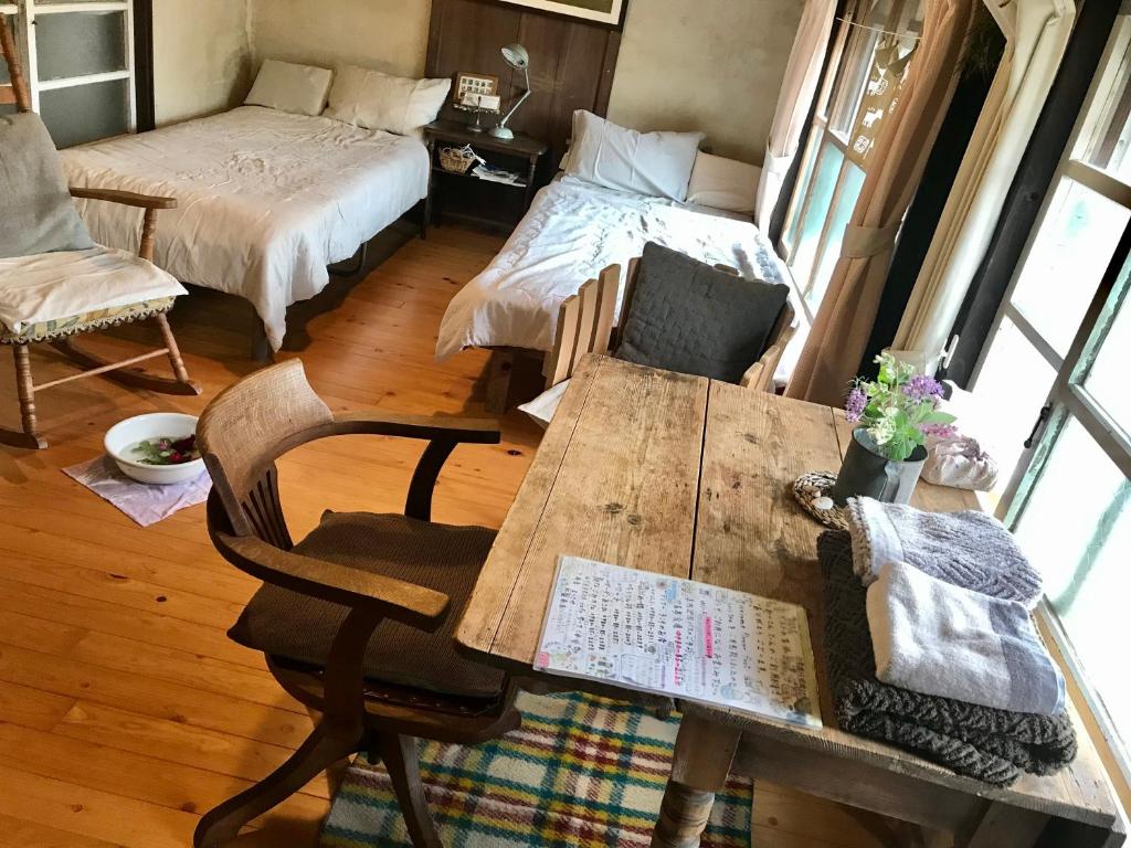 a room with a wooden table and a bed and a table and chairs at Travelers House おーさんてぃん青空舎 in Taketomi