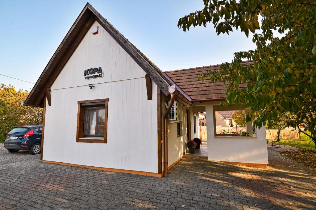 un edificio blanco con techo marrón en Kopa vendégház, en Szigetvár
