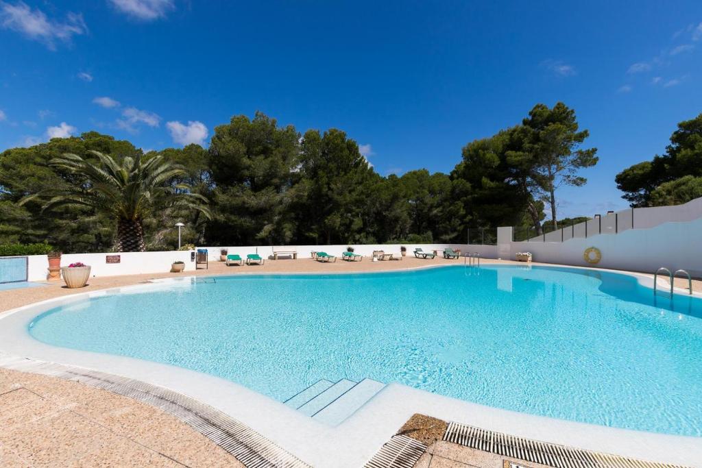 uma grande piscina com cadeiras e árvores em Disfruta del Paraiso em Son Parc