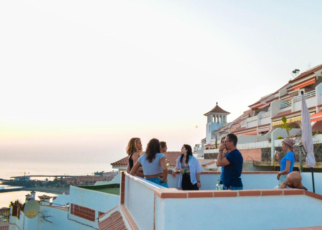 Grupa ludzi stoi na dachu i patrzy na ocean w obiekcie Banana Surf House w mieście Los Cristianos