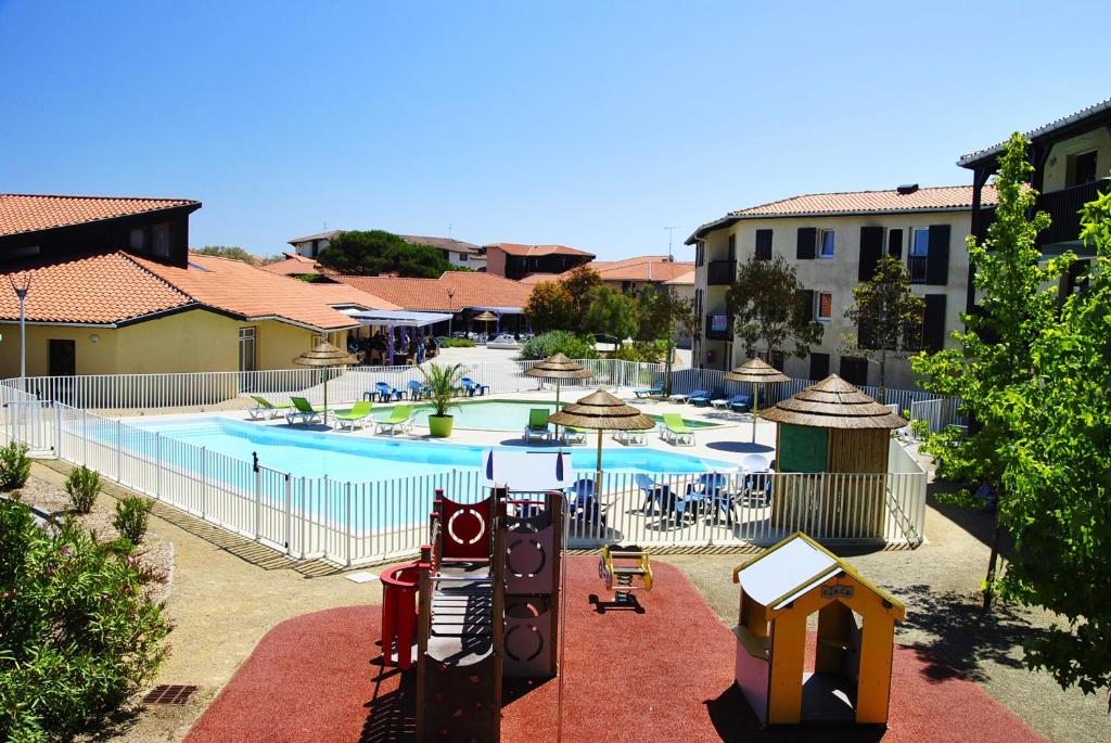 une grande piscine avec une aire de jeux et un bâtiment dans l'établissement Village Vacances Le Junka, à Vieux-Boucau-les-Bains