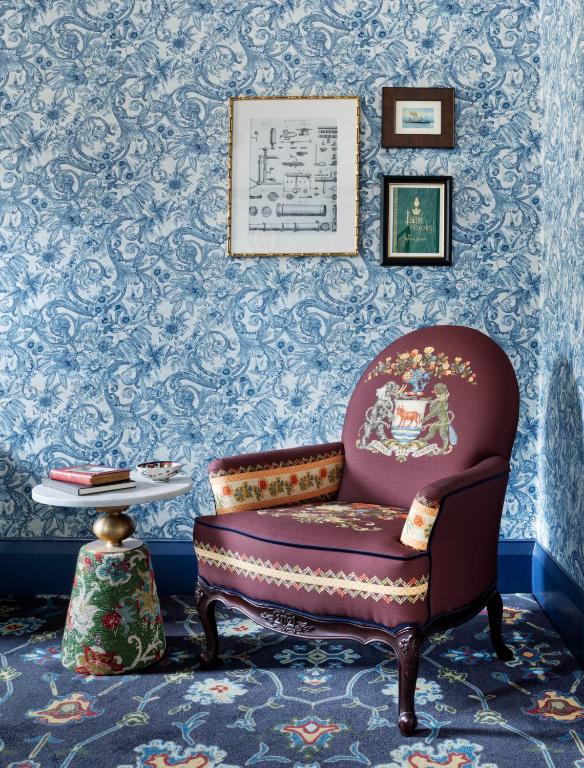 a chair and a table in a room with wallpaper at The Randolph Hotel Oxford, a Graduate by Hilton Hotel in Oxford