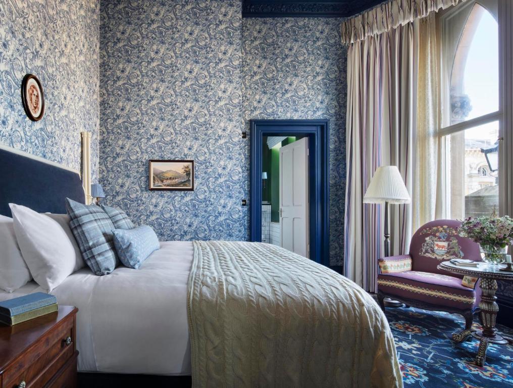 a bedroom with a bed and a chair and a window at The Randolph Hotel Oxford, a Graduate by Hilton Hotel in Oxford
