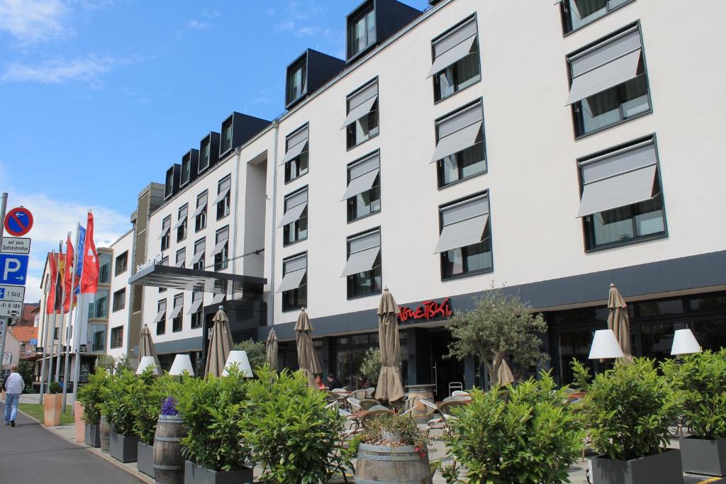 ein Gebäude mit Sonnenschirmen und Pflanzen davor in der Unterkunft Hotel Schweizer Hof in Kassel