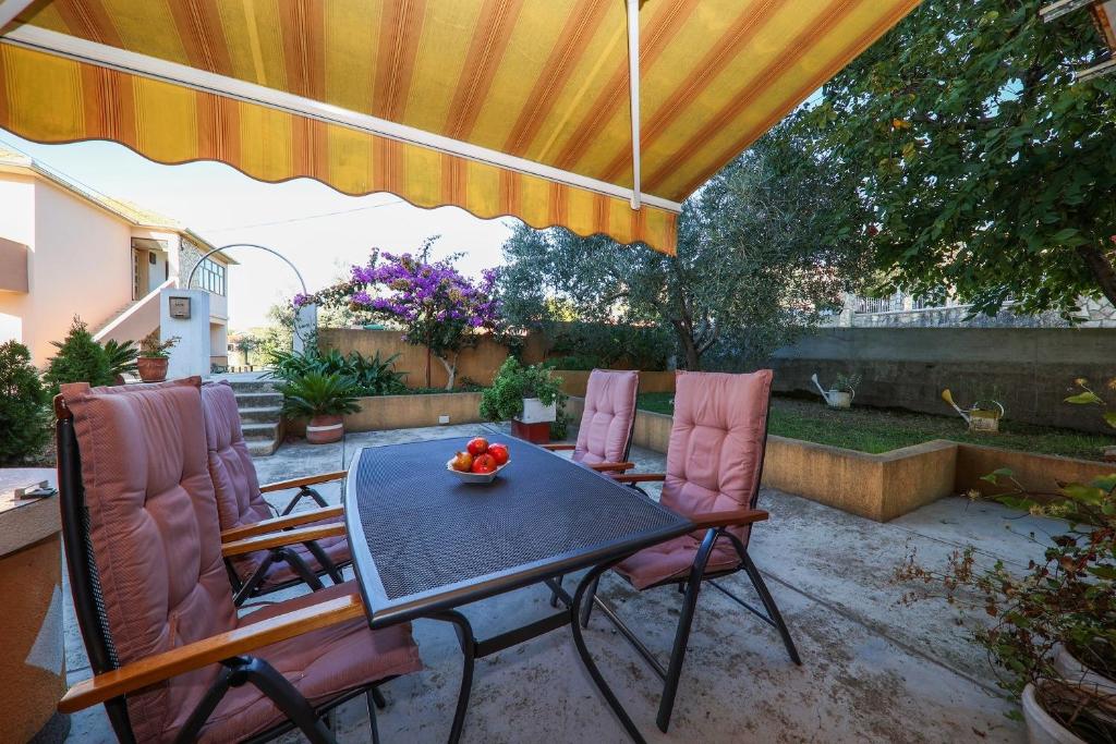 een patio met een tafel en stoelen onder een parasol bij Apartment Gašpe - garden terrace in Sutomišćica