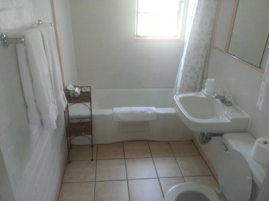 a bathroom with a sink and a tub and a toilet at Bishop Village Motel in Bishop