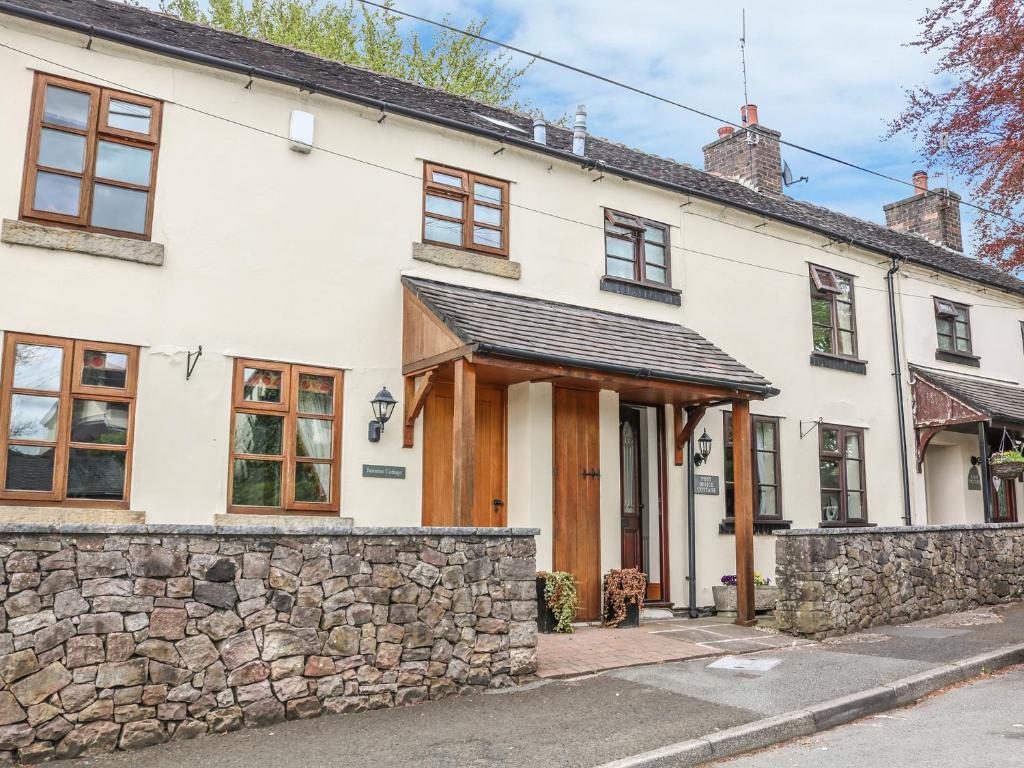 a white house with a stone wall at Post Office Cottage in Endon