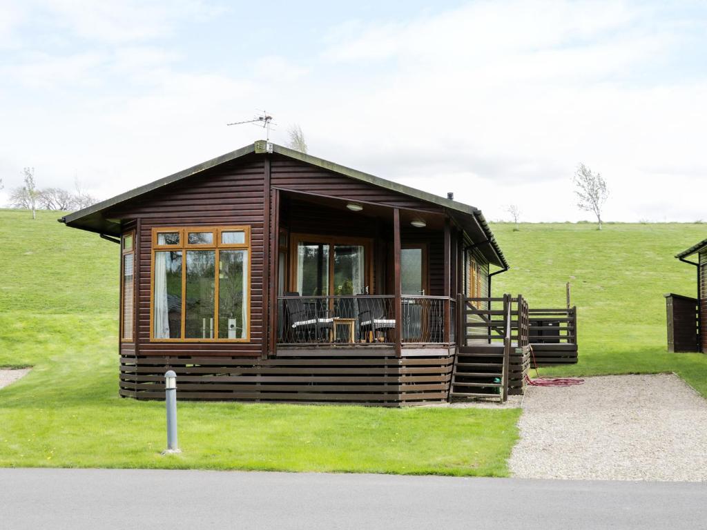 a log cabin with a porch and chairs in a field at 16 Badgers Retreat in Richmond