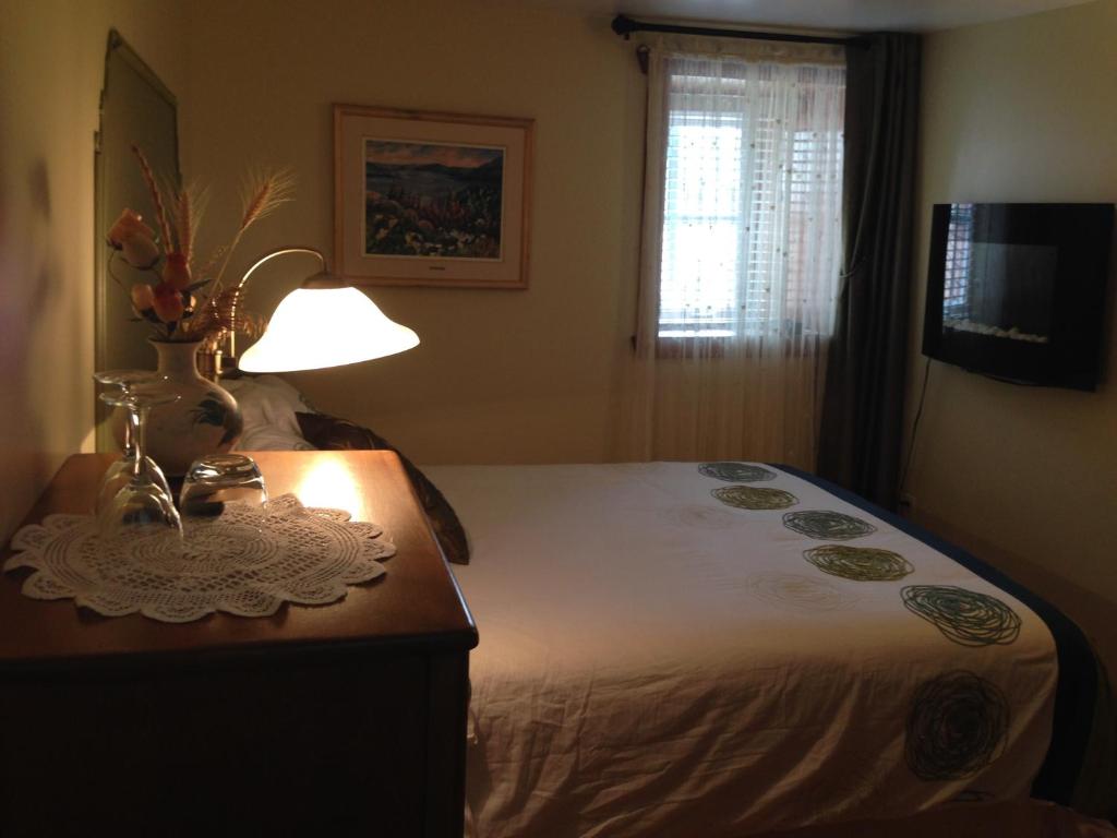 1 dormitorio con 1 cama y 1 mesa con lámpara en Auberge La Fjordelaise & la Rosalie, en L'Anse-Saint-Jean