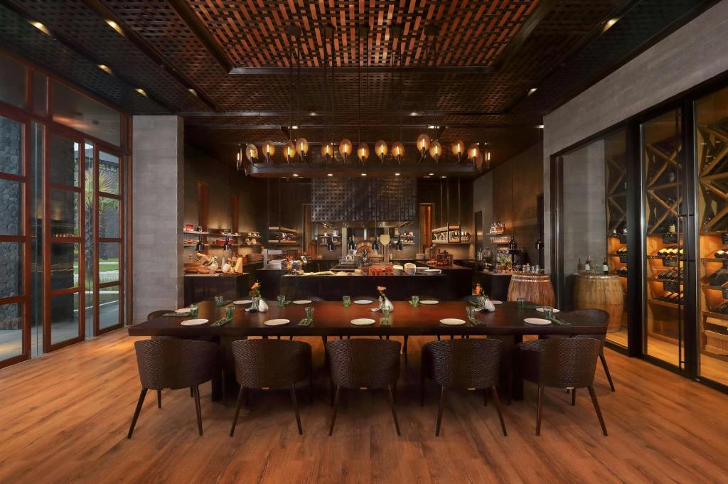 a restaurant with a table and chairs and a bar at Radisson Blu Bali Uluwatu in Uluwatu