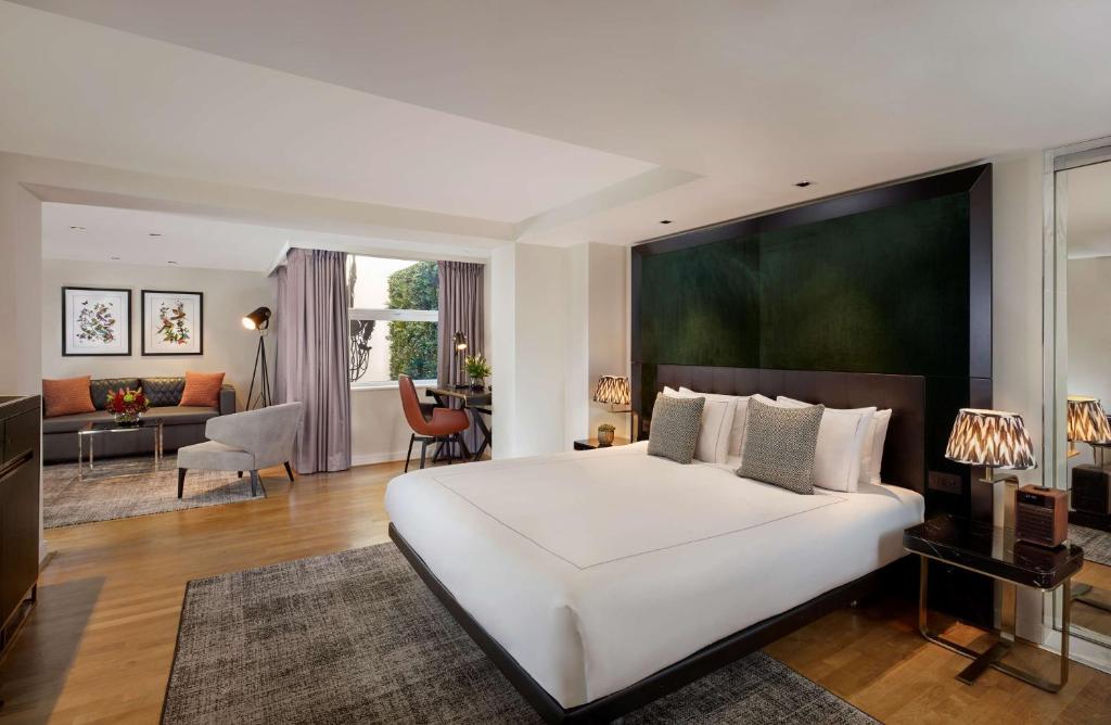 a bedroom with a large white bed and a living room at Holmes Hotel London in London