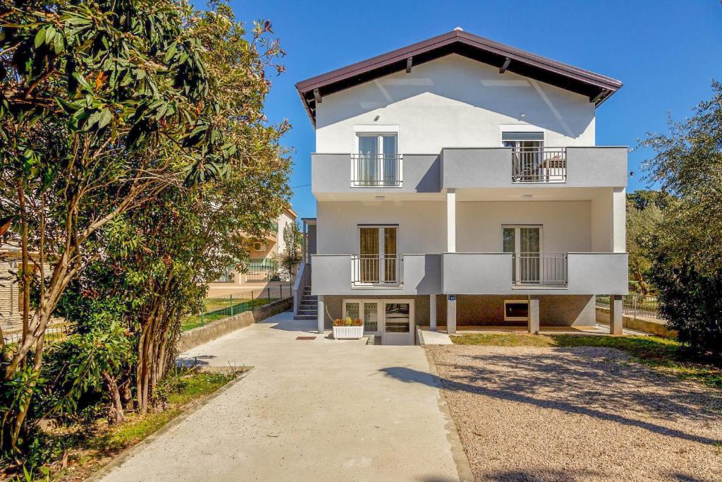 Casa blanca con balcón y árboles en Apartment Lea, en Sveti Filip i Jakov