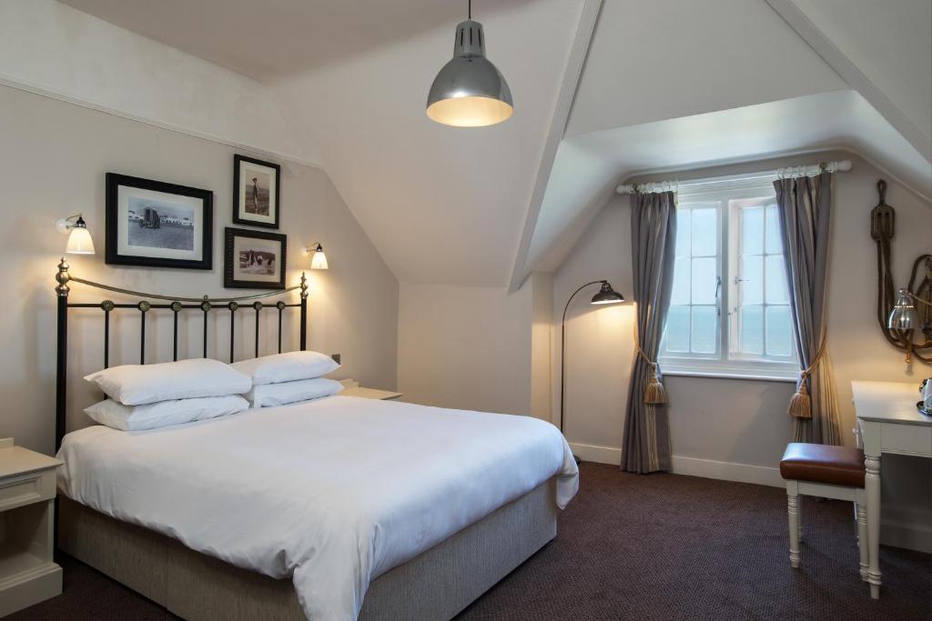 a bedroom with a large white bed and a window at The Marine in Whitstable