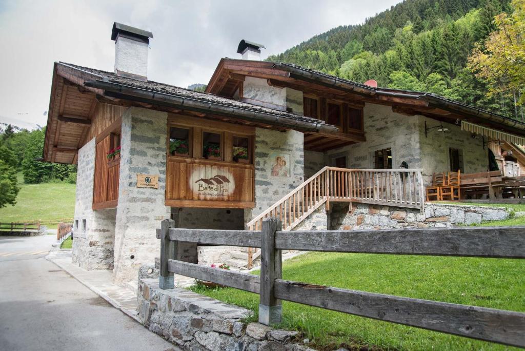 a log cabin with a porch and a fence at Baite Di Pra in Spiazzo