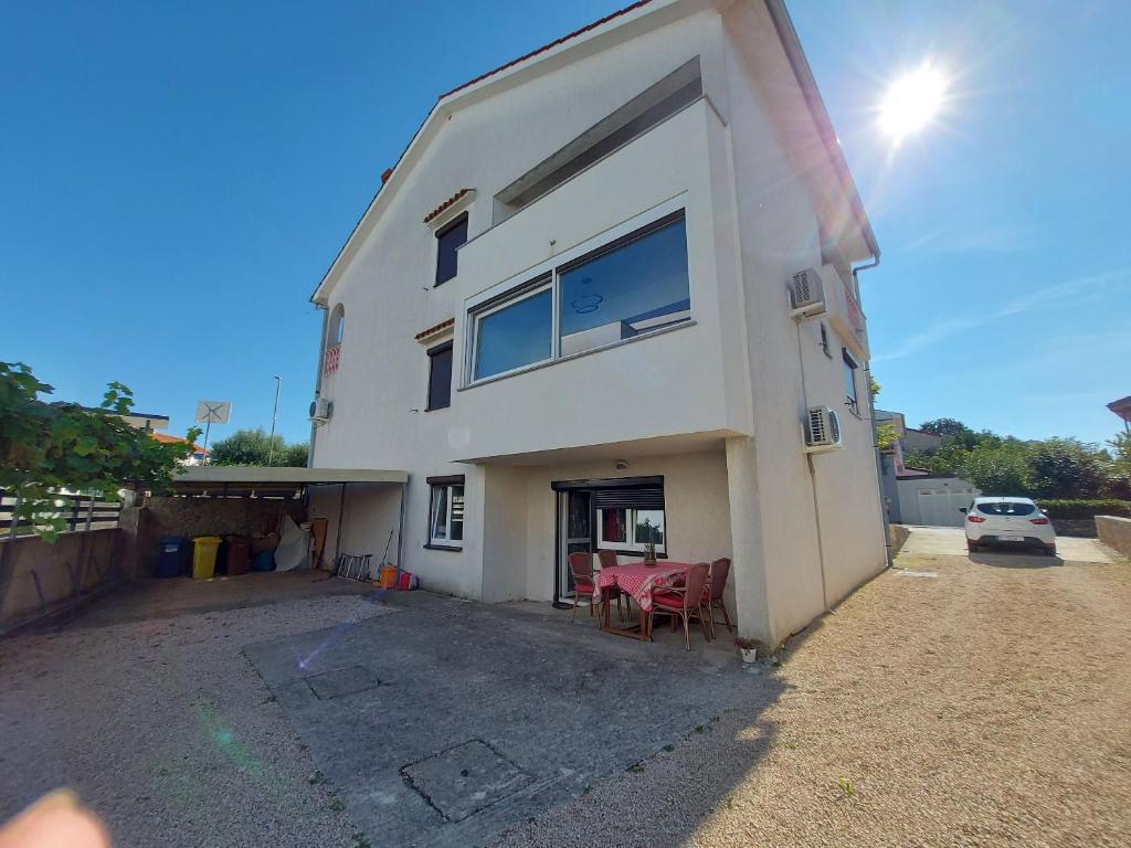 un bâtiment blanc avec des chaises rouges dans un parking dans l'établissement Apartments Bernarda, à Krk