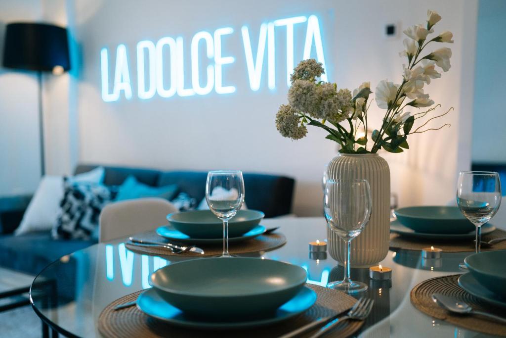 une table avec des assiettes et des verres et un vase avec des fleurs dans l'établissement Apartment Black Level, 30m playa, Pool, Wifi, à Almería