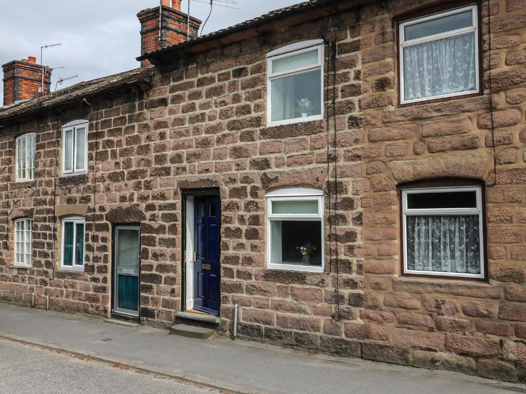 un edificio de ladrillo con una puerta y ventanas azules en The Hill, en Matlock