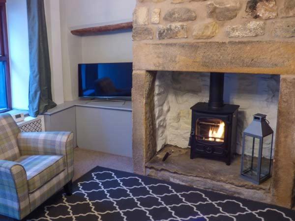 Una sala de estar con chimenea de piedra y un sofá. en 88 Regent Street, en Waddington