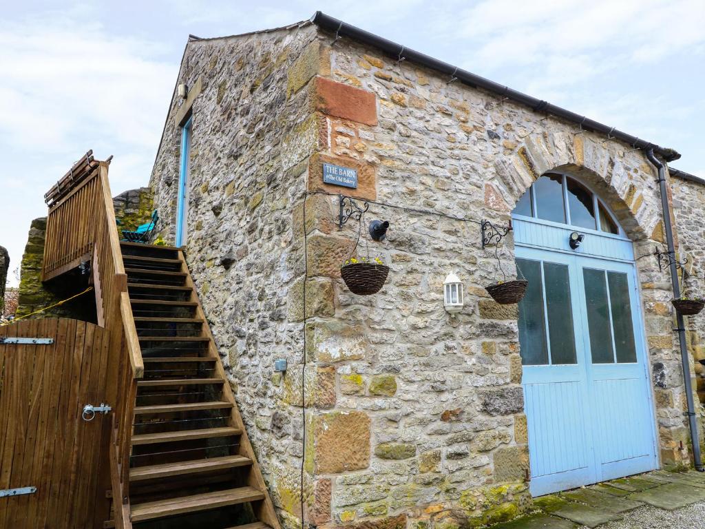 a stone building with a blue door and stairs at The Old Bakery Barn in Bakewell