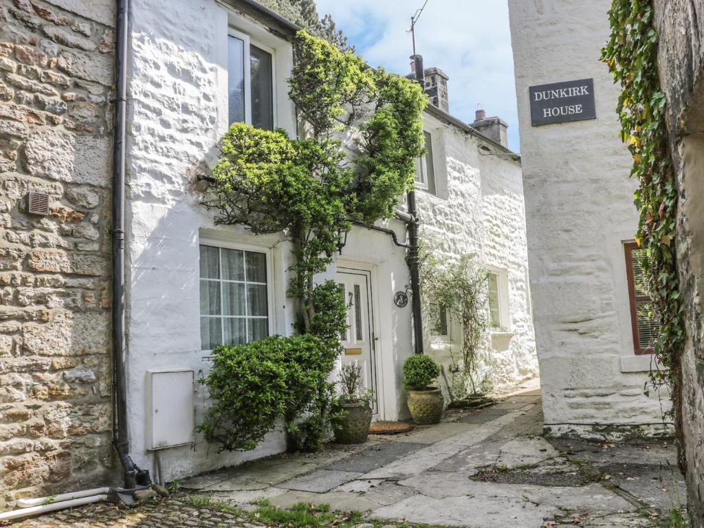 a white house with a white door and ivy at 8 Stonegate in High Bentham