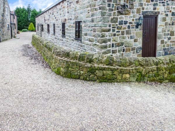 un edificio de piedra con una puerta a un lado en Moorlands Farm Cottage en Foxt